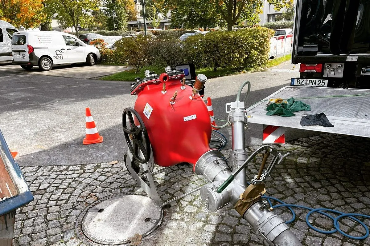 Technik zum Einbau eines Schlauchliners an einem geöffneten Schacht auf Kopfsteinpflaster